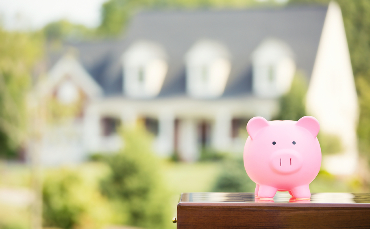 loi assurance emprunteur – Une tirelire en forme de cochon avec une maison en arrière-plan