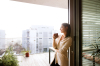 assurance emprunteur – Une femme sur son balcon en train de boire une boisson chaude