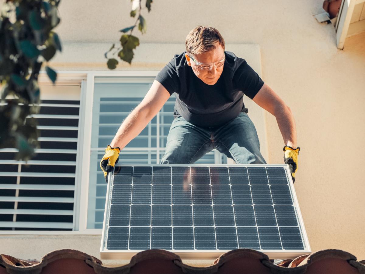 intelligence artificielle immobilier – Un ouvrier en train de poser un panneau photovoltaïque
