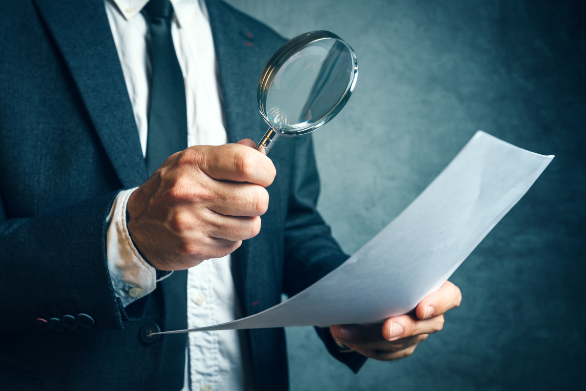 Comment faire une demande de TMA ? Un homme regarde un papier à la loupe