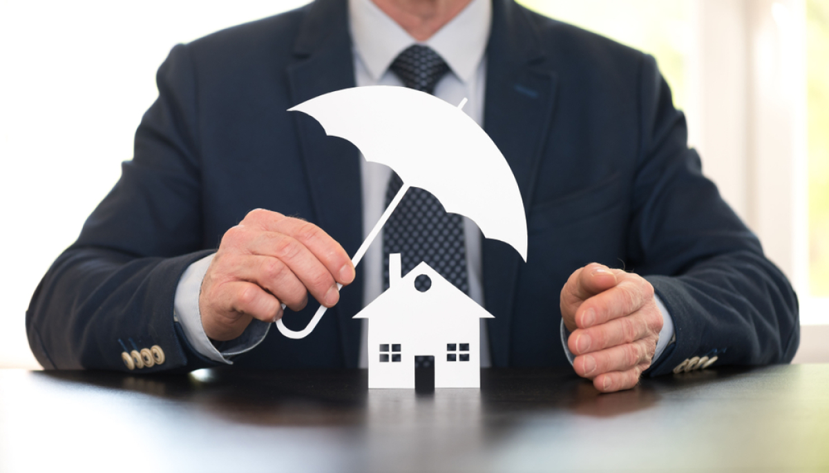 Malfaçons appartement neuf — Un homme tient un parapluie au-dessus d'une maison