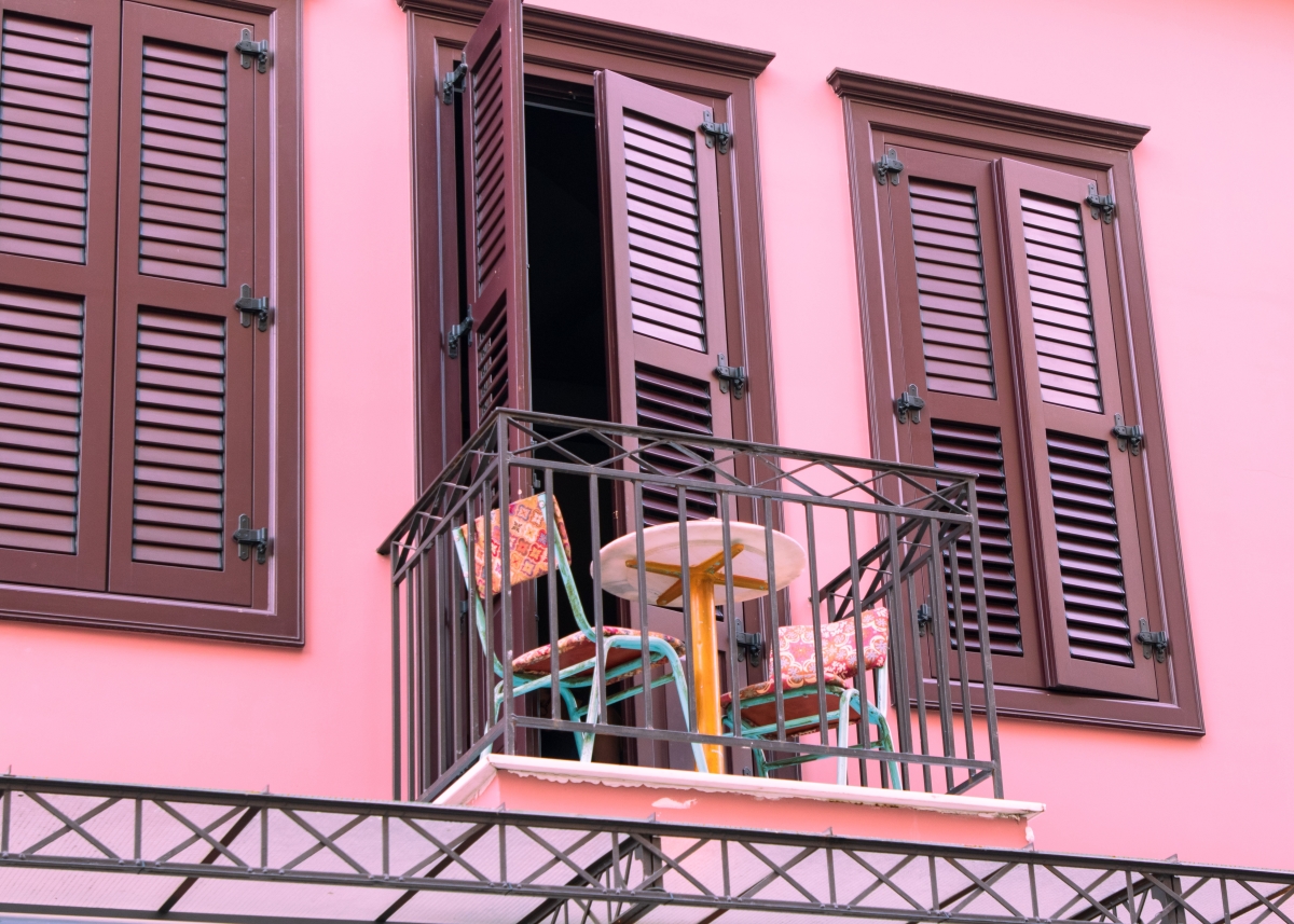  un balcon minuscule avec une table et deux chaises devant un mur rose