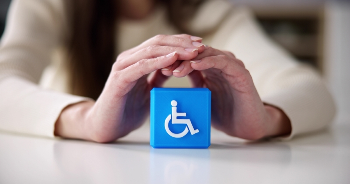plusieurs dispositifs d'aide à l'achat immobilier existent pour les PMR deux mains qui protègent un symbole de handicap sur un cube bleu