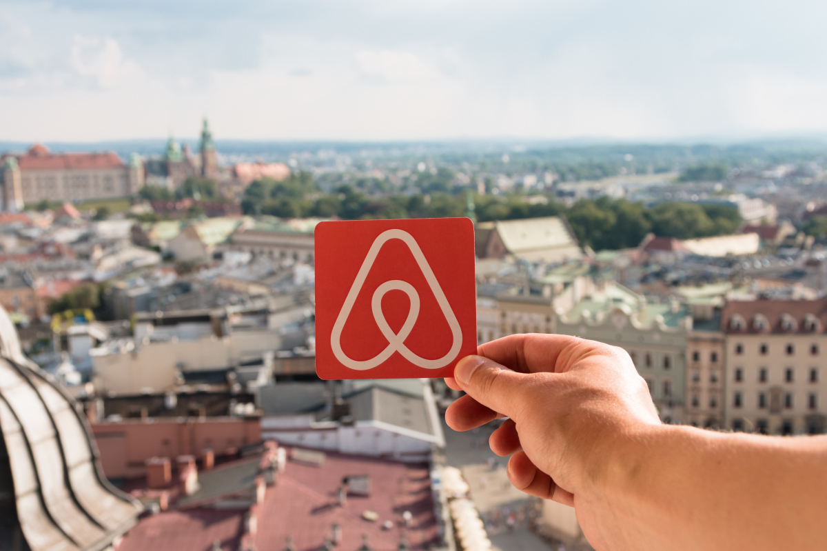 Une femme tient dans sa main le logo Airbnb