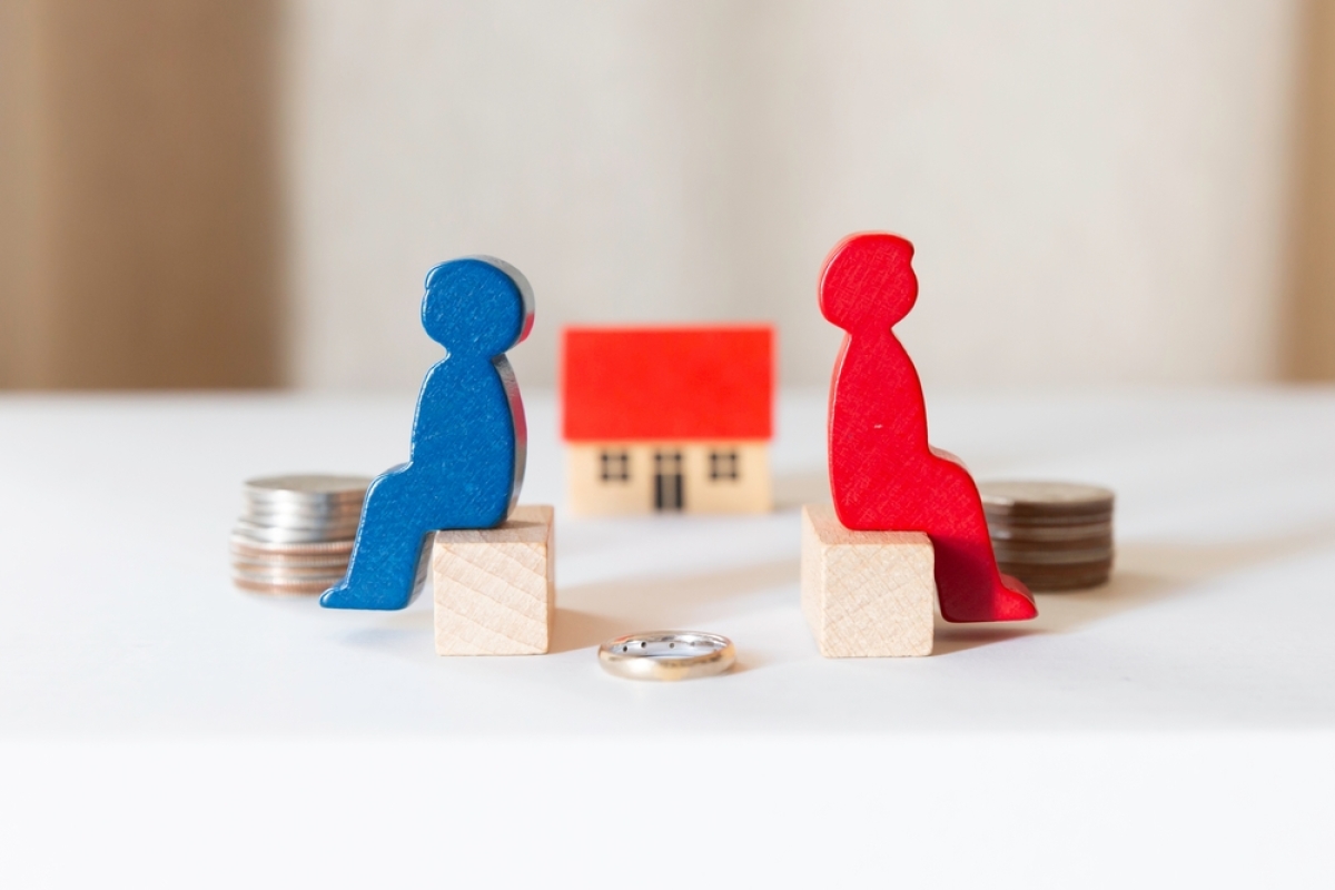les options en matière de régime matrimonial sont nombreuses. 2 personnages en bois dos à dos avec une maison en fond flou